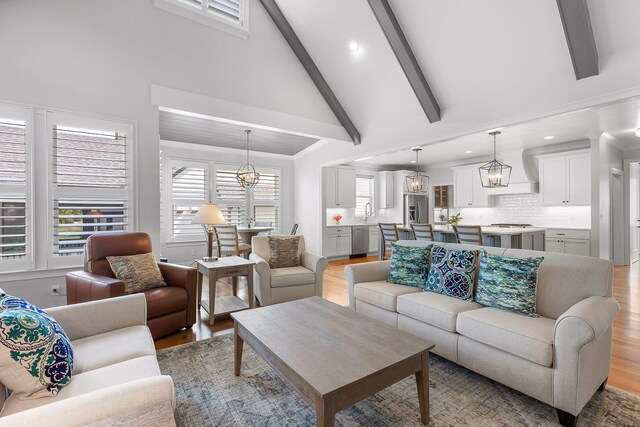 living room with beam ceiling, light wood-type flooring, and high vaulted ceiling