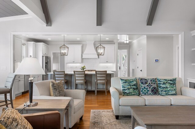 living room featuring beamed ceiling, light hardwood / wood-style flooring, and crown molding