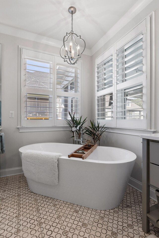 bathroom featuring a notable chandelier, a washtub, and crown molding