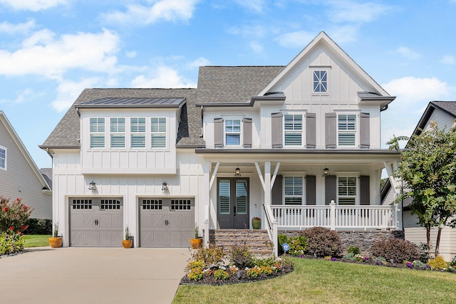 view of front of house with covered porch, a garage, and a front lawn