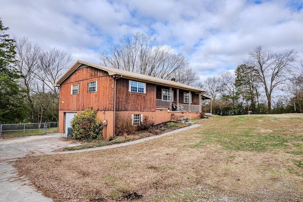 view of property exterior with a lawn, a porch, and a garage