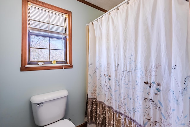 bathroom with toilet, ornamental molding, and a shower with shower curtain