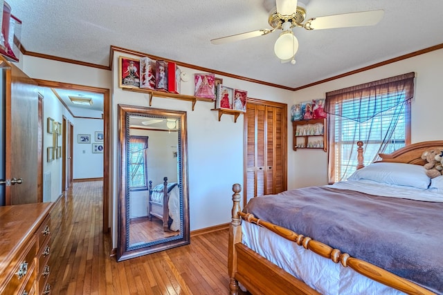 bedroom featuring a textured ceiling, ceiling fan, wood-type flooring, a closet, and crown molding