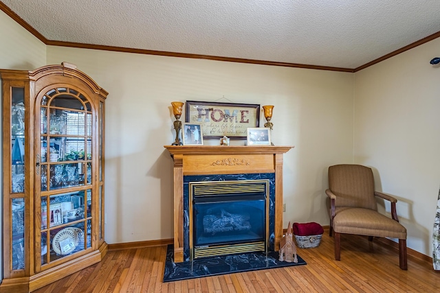 sitting room with hardwood / wood-style flooring, a premium fireplace, crown molding, and a textured ceiling