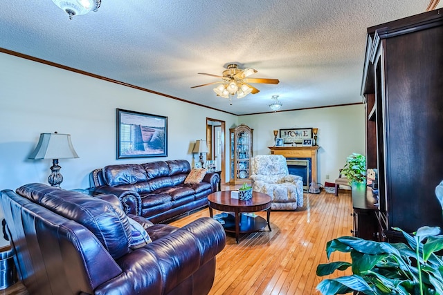 living room with a textured ceiling, ceiling fan, light hardwood / wood-style flooring, and crown molding