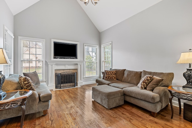 living room featuring hardwood / wood-style floors, high vaulted ceiling, plenty of natural light, and a tiled fireplace