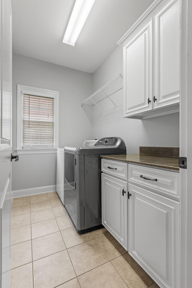 laundry area featuring cabinets, light tile patterned floors, and washing machine and clothes dryer