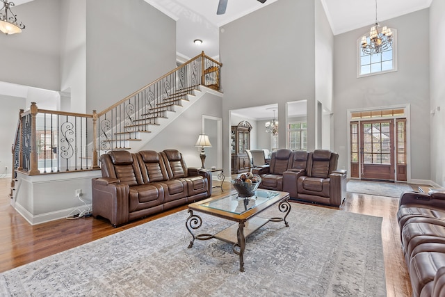 living room featuring hardwood / wood-style floors, a towering ceiling, ceiling fan with notable chandelier, and ornamental molding