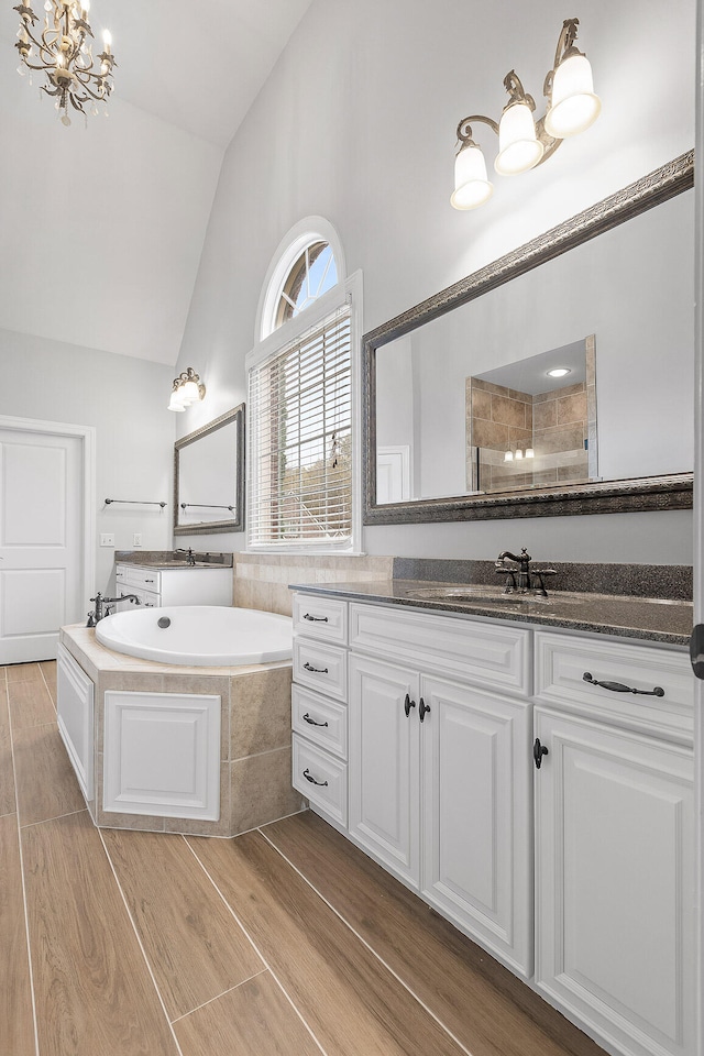 bathroom with vanity, an inviting chandelier, plus walk in shower, and vaulted ceiling