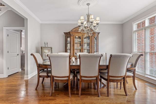 dining area with ornamental molding, a notable chandelier, and wood-type flooring