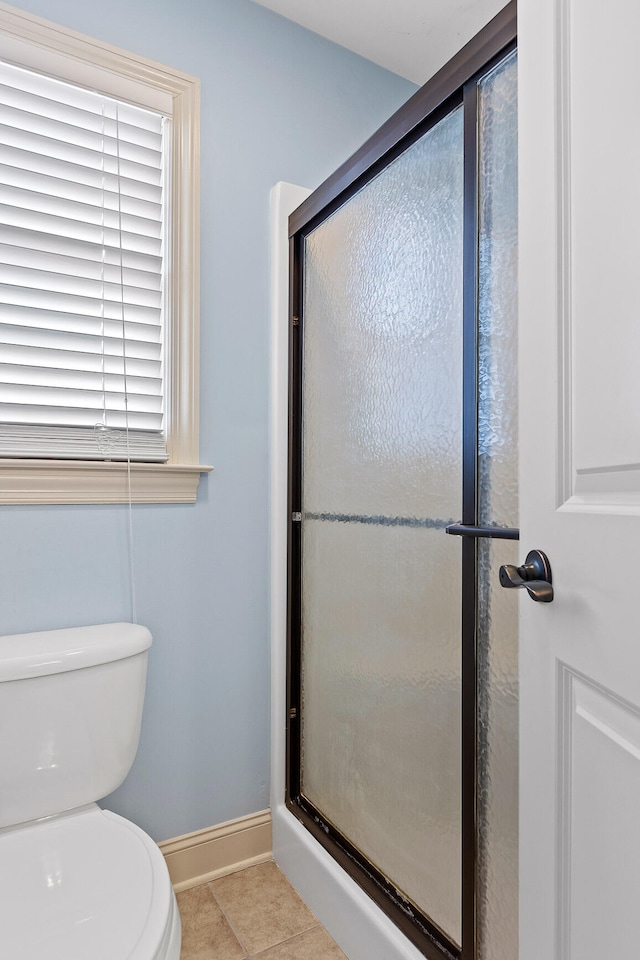 bathroom featuring toilet, tile patterned floors, and a shower with shower door