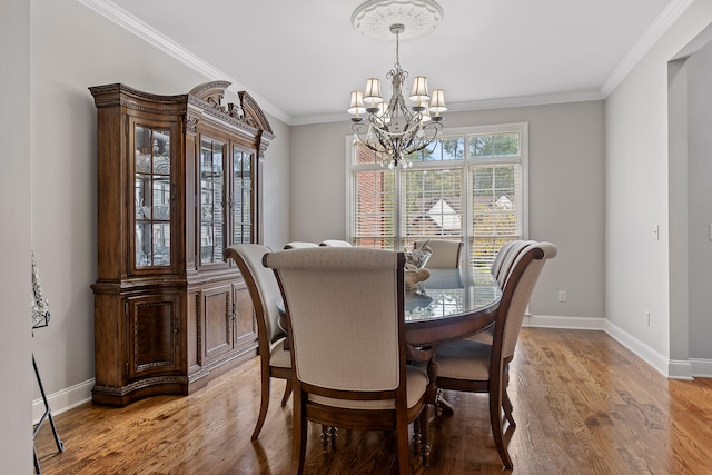 dining area featuring crown molding, light hardwood / wood-style floors, and an inviting chandelier