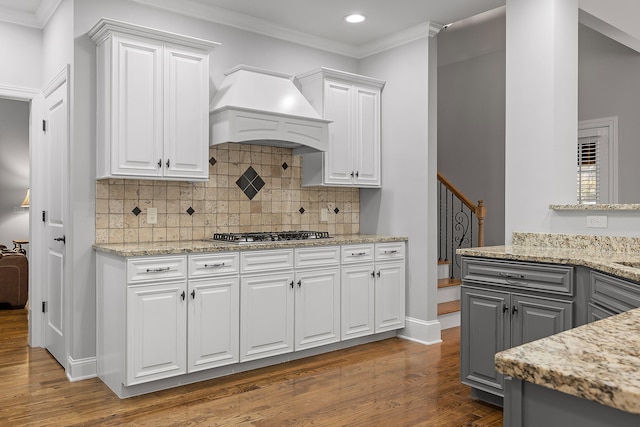 kitchen featuring backsplash, custom range hood, dark hardwood / wood-style flooring, light stone counters, and white cabinetry