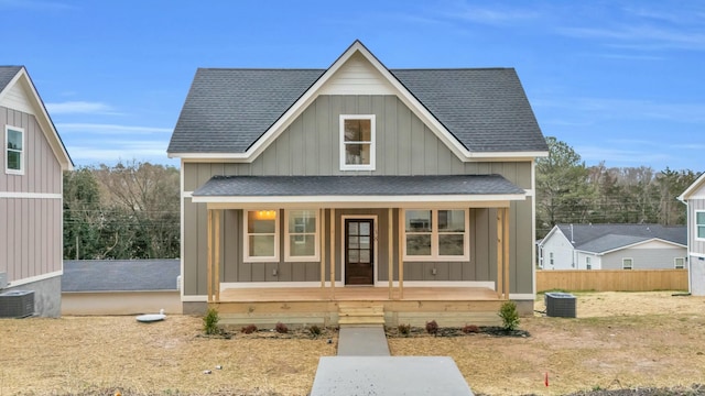 view of front facade with roof with shingles, a porch, board and batten siding, and central AC unit