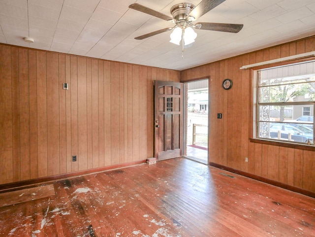 spare room featuring hardwood / wood-style flooring, ceiling fan, and wood walls