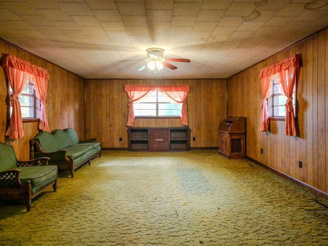 unfurnished room with carpet flooring, ceiling fan, and wood walls