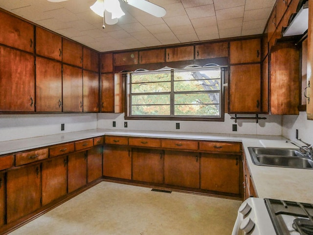 kitchen with ceiling fan, sink, white range, and wooden walls