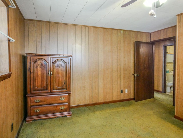 unfurnished bedroom with ensuite bath, wood walls, and light colored carpet