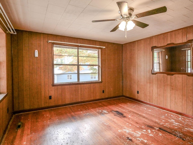 unfurnished room featuring dark hardwood / wood-style flooring, ceiling fan, and wood walls