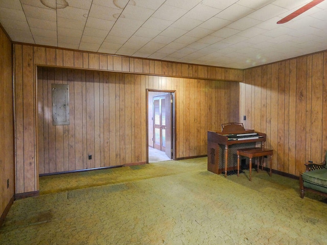 interior space featuring light carpet, electric panel, ceiling fan, and wood walls