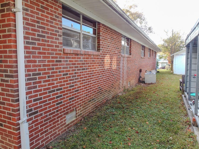 view of side of home featuring a lawn and central AC