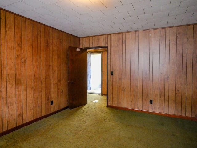 carpeted spare room featuring wood walls