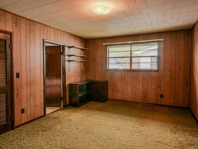 unfurnished room featuring wooden walls and carpet