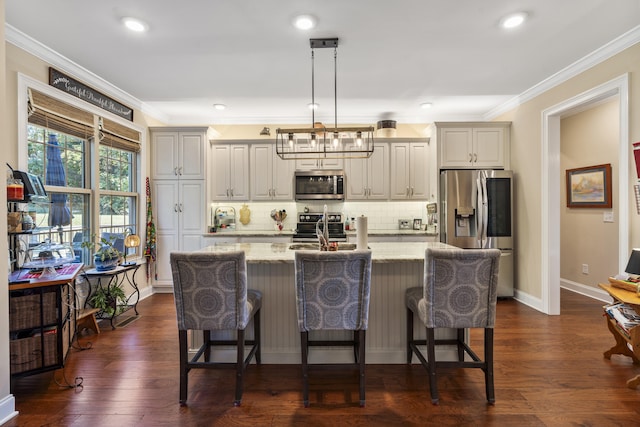 kitchen featuring light stone countertops, appliances with stainless steel finishes, dark hardwood / wood-style flooring, a kitchen island with sink, and hanging light fixtures