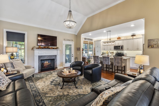 living room with vaulted ceiling, ornamental molding, a fireplace, dark hardwood / wood-style flooring, and a chandelier