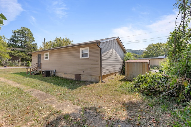 view of property exterior with a lawn, a storage unit, and central AC