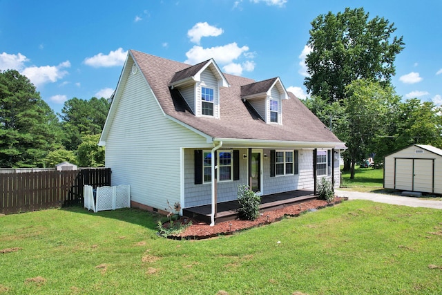 cape cod house featuring covered porch, a front yard, and a storage unit