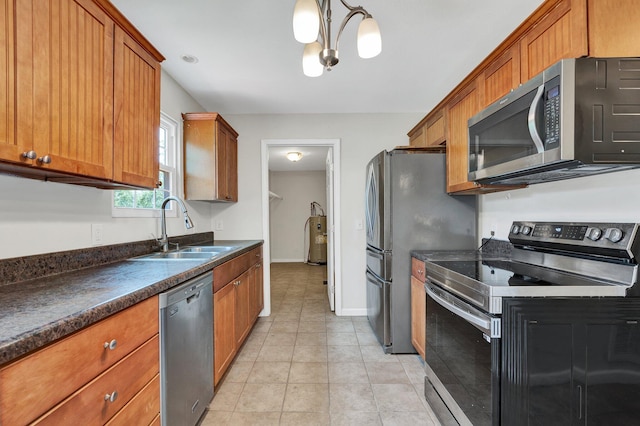 kitchen with electric water heater, hanging light fixtures, sink, appliances with stainless steel finishes, and light tile patterned flooring