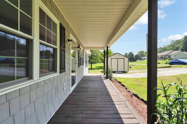 wooden deck featuring a yard, a porch, and a storage unit