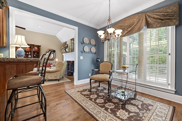 living area featuring crown molding, an inviting chandelier, a healthy amount of sunlight, and hardwood / wood-style flooring