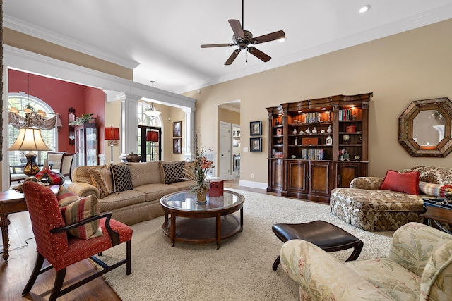 living room featuring ceiling fan with notable chandelier, decorative columns, hardwood / wood-style flooring, and ornamental molding