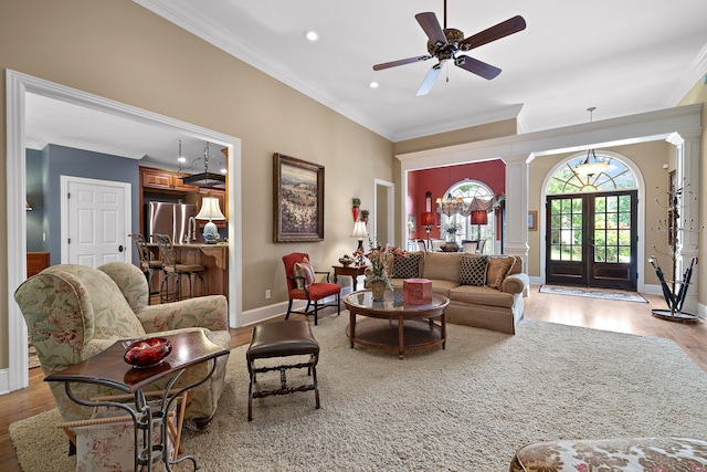 living room featuring ornate columns, ceiling fan, french doors, crown molding, and light wood-type flooring