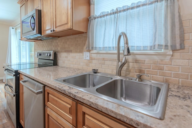 kitchen with sink, light hardwood / wood-style flooring, light stone countertops, tasteful backsplash, and stainless steel appliances