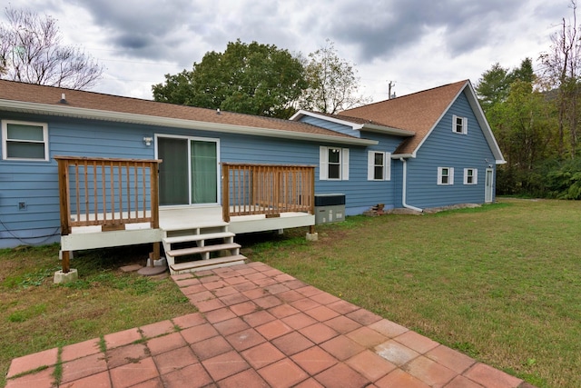 back of property featuring a deck and a lawn