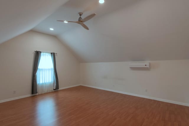 bonus room featuring a wall mounted AC, wood-type flooring, ceiling fan, and lofted ceiling