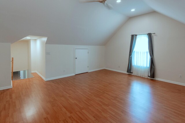 bonus room with light wood-type flooring and vaulted ceiling