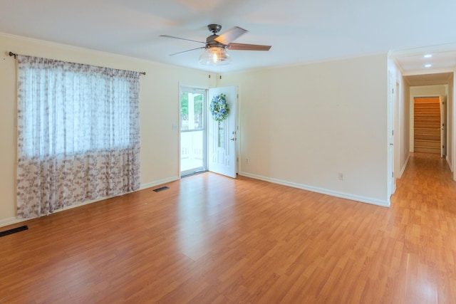 empty room with ceiling fan, crown molding, and light hardwood / wood-style flooring