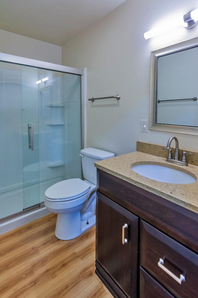 bathroom featuring toilet, vanity, an enclosed shower, and hardwood / wood-style flooring