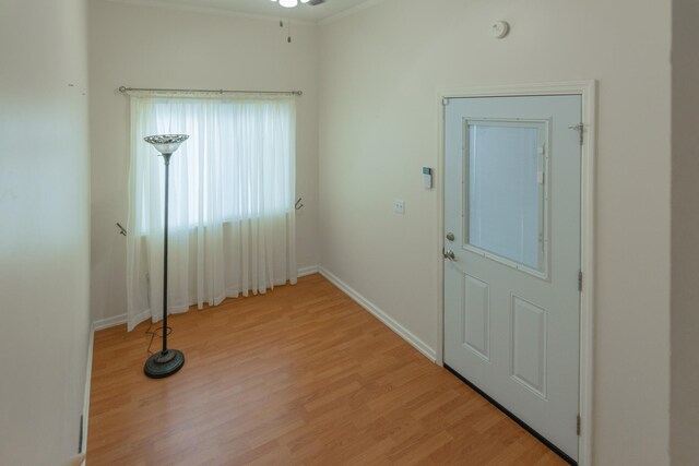 interior space with ceiling fan, ornamental molding, and light wood-type flooring