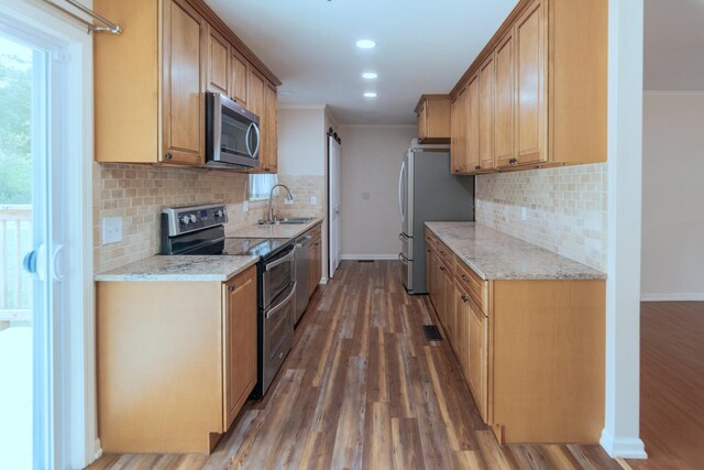 kitchen with sink, stainless steel appliances, light stone counters, dark hardwood / wood-style floors, and crown molding