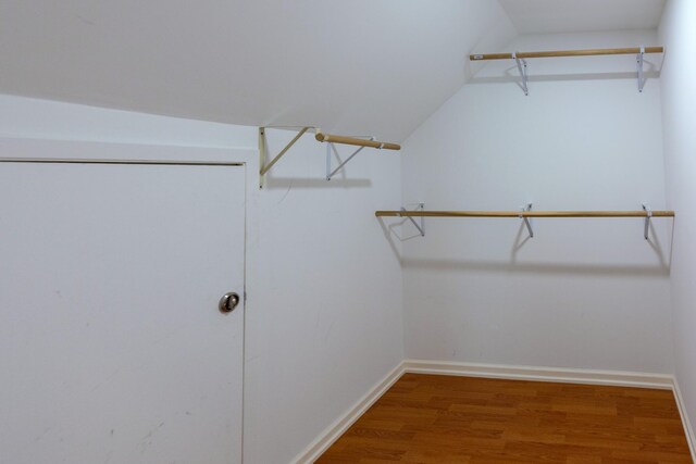 walk in closet with wood-type flooring and vaulted ceiling