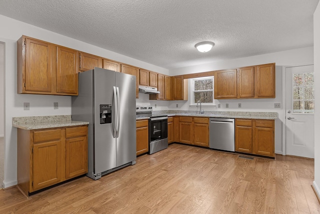 kitchen featuring sink, light hardwood / wood-style flooring, a textured ceiling, and appliances with stainless steel finishes