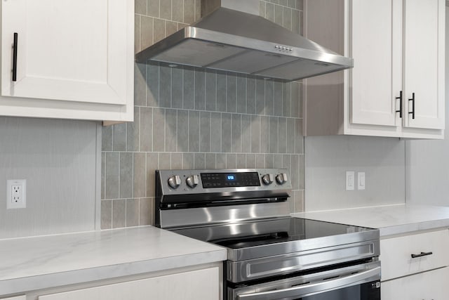 kitchen with white cabinets, wall chimney exhaust hood, backsplash, and stainless steel range with electric cooktop