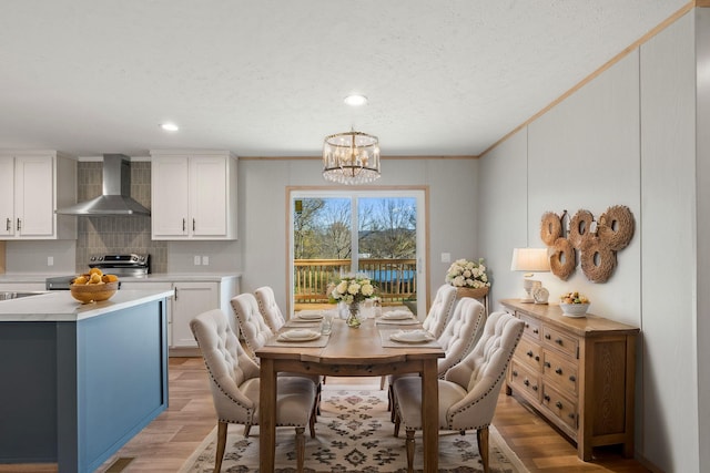 dining area with light wood-type flooring, crown molding, and an inviting chandelier