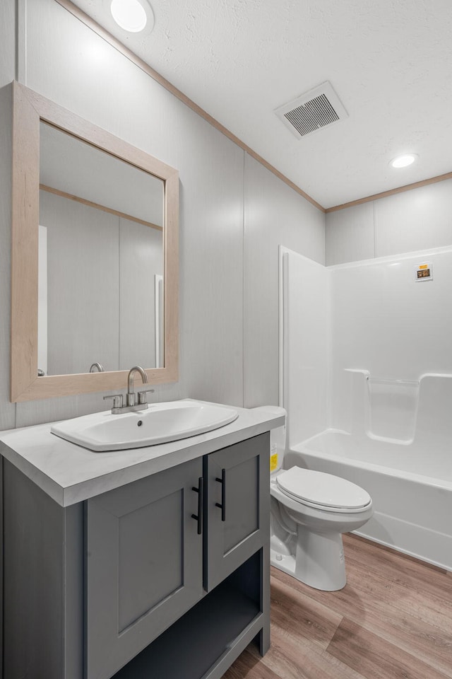 full bathroom with shower / bath combination, vanity, wood-type flooring, and toilet