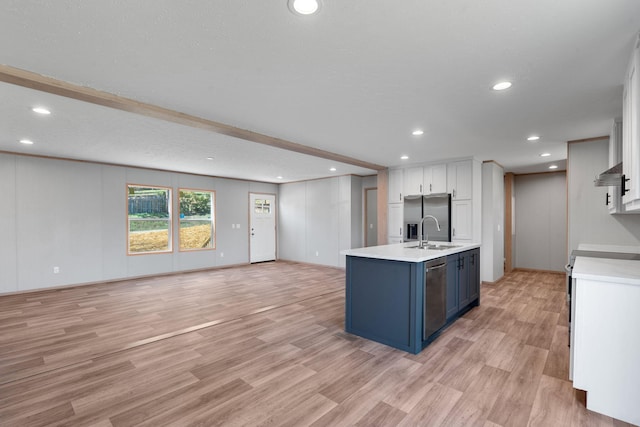 kitchen with appliances with stainless steel finishes, blue cabinets, sink, light hardwood / wood-style flooring, and white cabinets